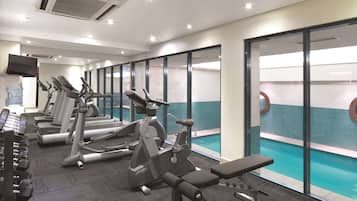 Un gimnasio con cintas de correr, elípticas y bancos de pesas.
