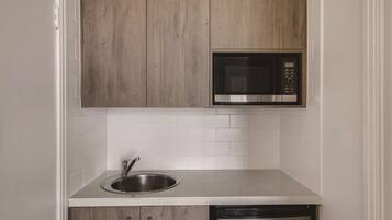 Cozinha com pia de aço inoxidável, micro-ondas e lava-louças embutidas nos armários.