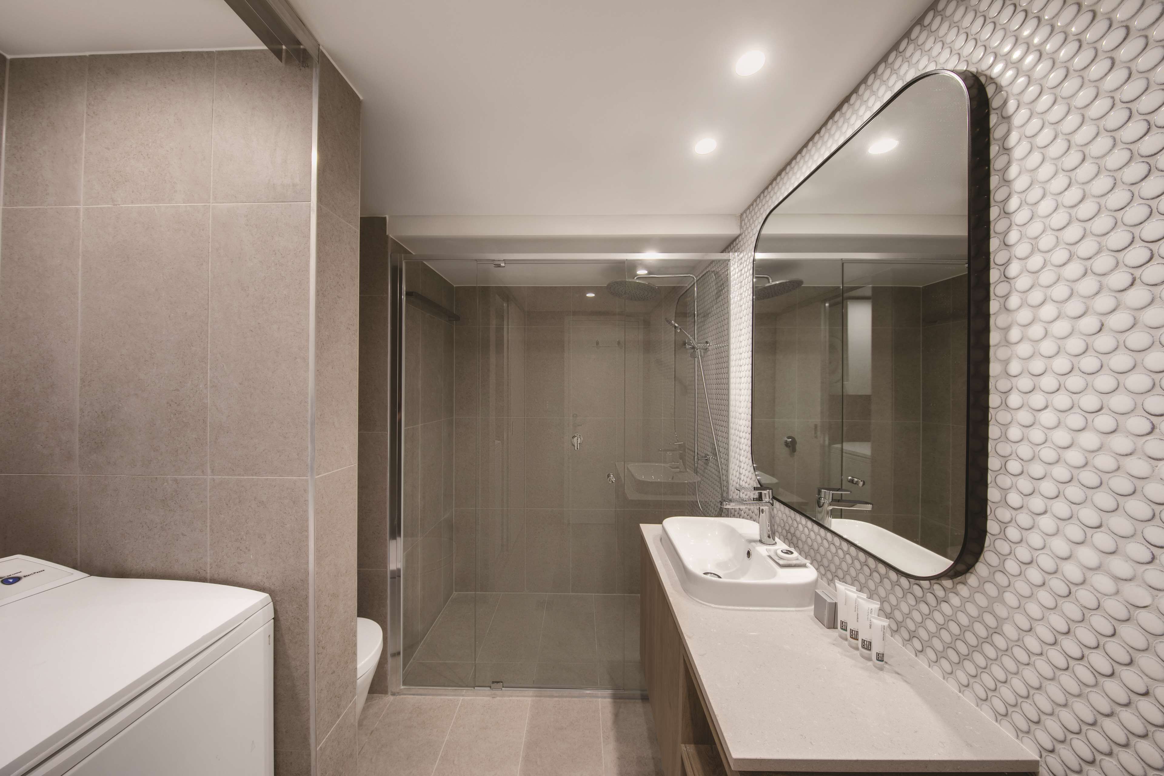 A modern bathroom with a walk-in shower, a large mirror, and a vanity with a sink.
