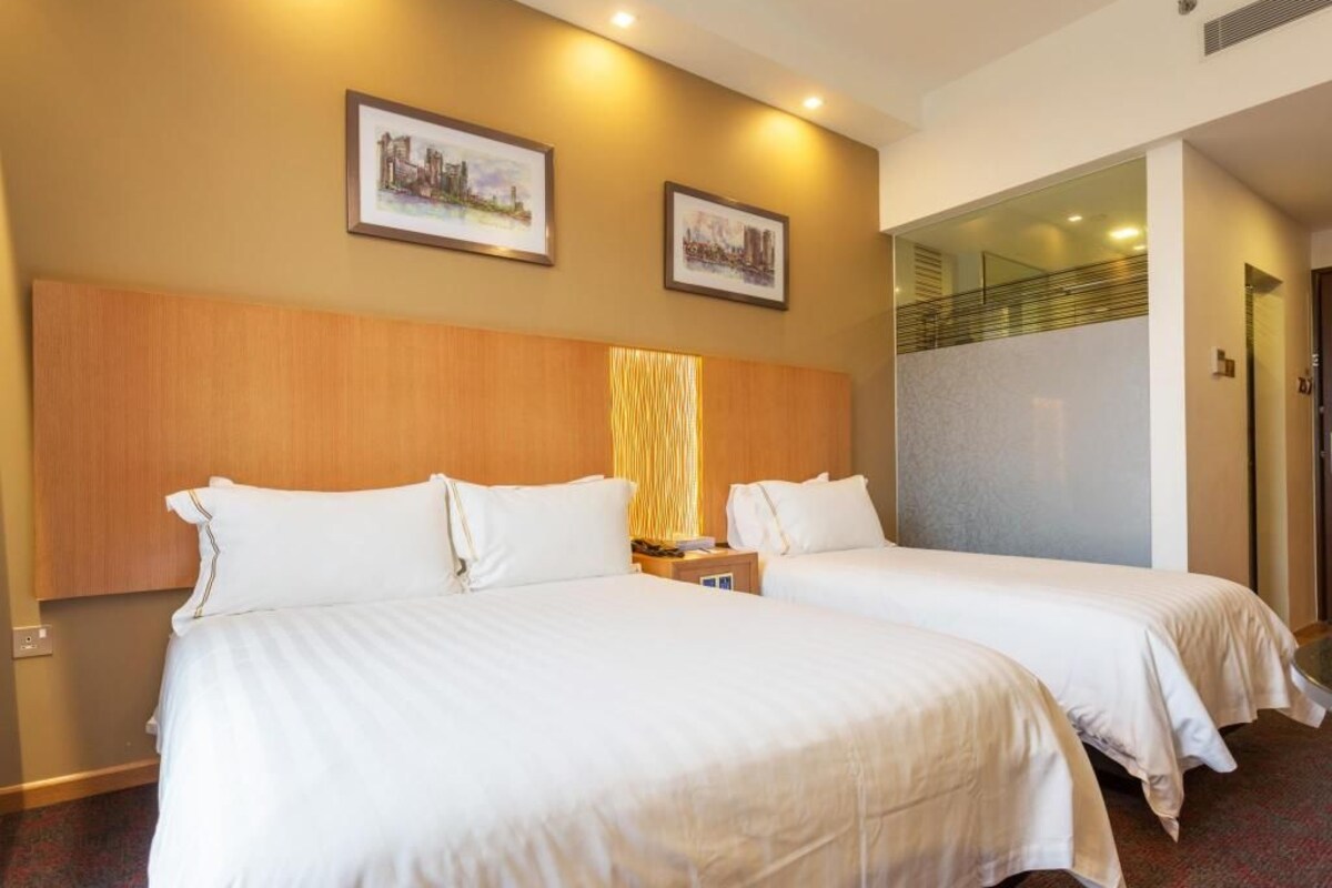 A hotel room with two beds, a wooden headboard, and two framed pictures on the wall.