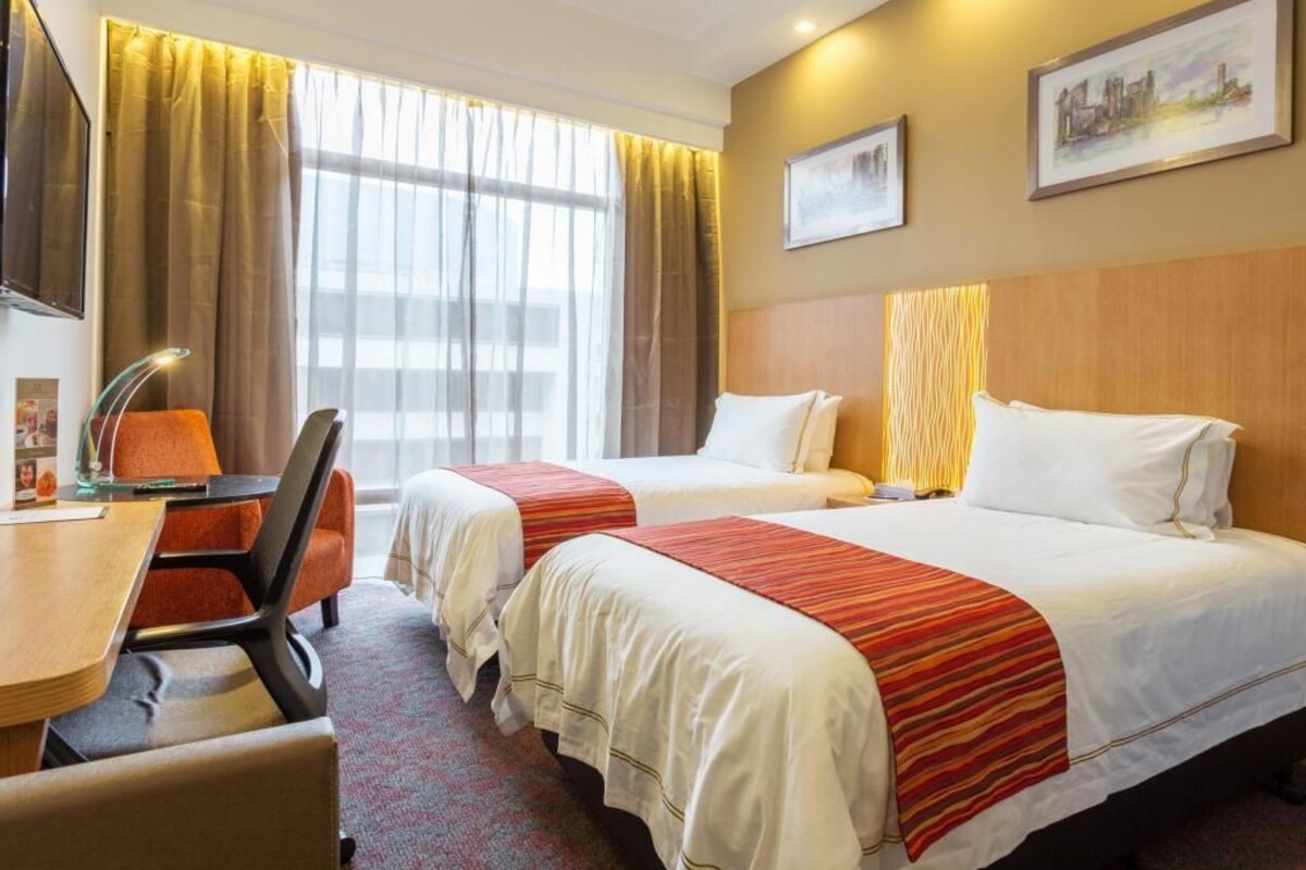 A hotel room with two beds, a desk, and a chair.