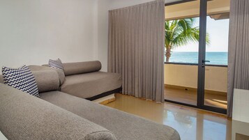 Un salón moderno con sofá y un amplio ventanal con vistas al océano.