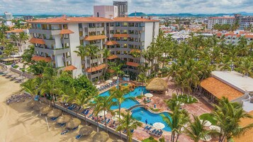 Un hotel con piscina, palmeras y playa.