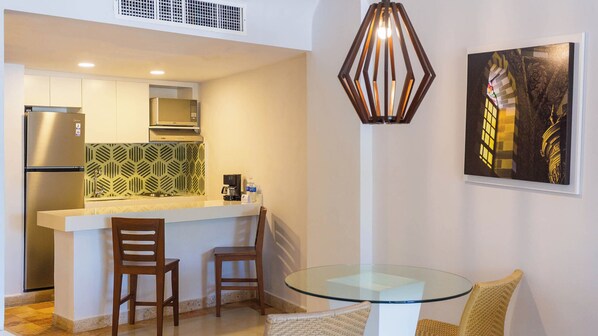 A compact kitchen with modern appliances, a patterned backsplash, and a dining area with a glass table and wicker chairs. - Luna Palace Hotel and Suites (Mazatlán)