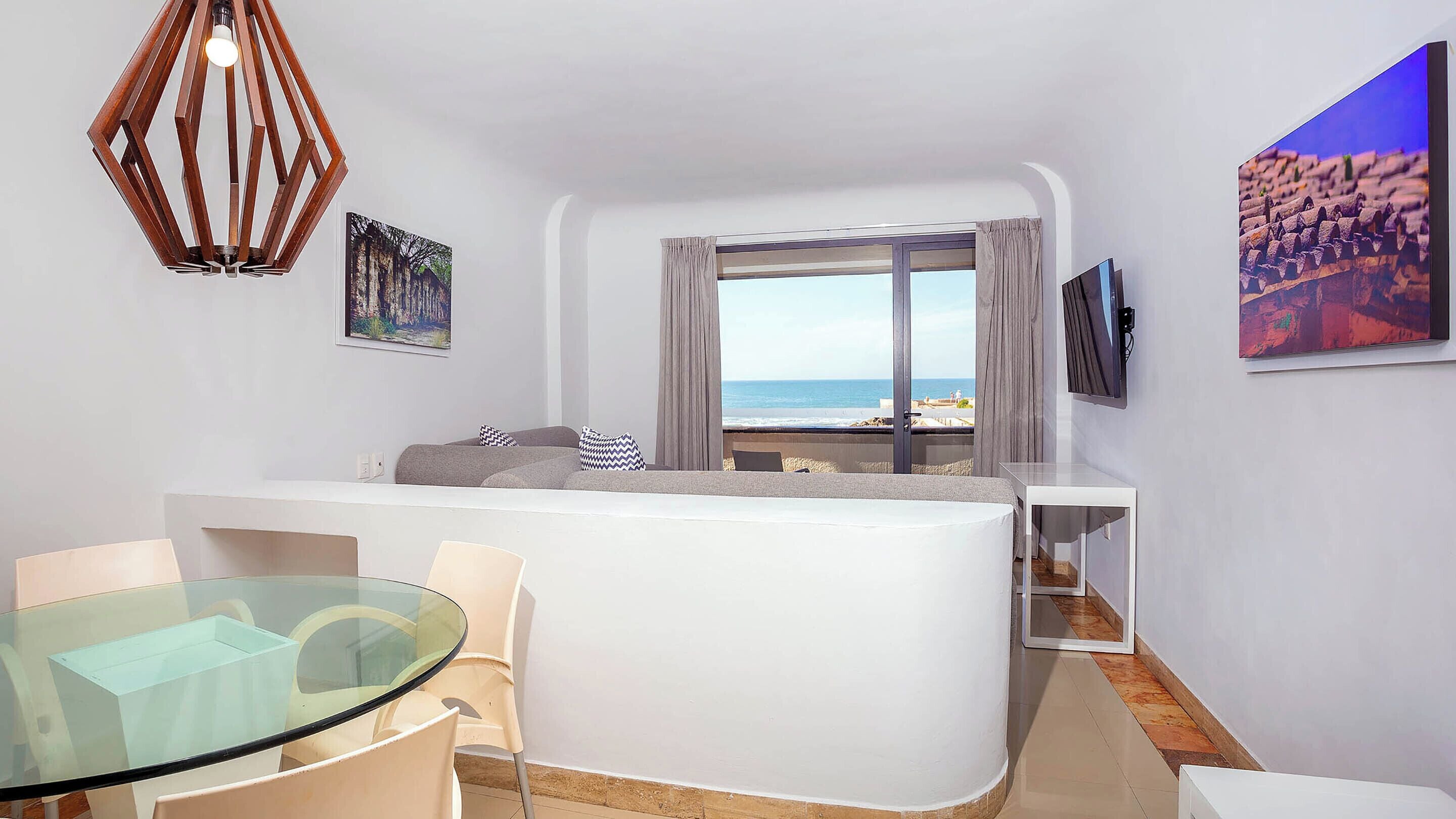 Une chambre moderne avec une table en verre, un canapé blanc et une vue sur la plage.