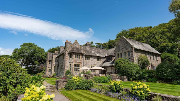 A large stone building with a well-maintained garden and outdoor seating area.