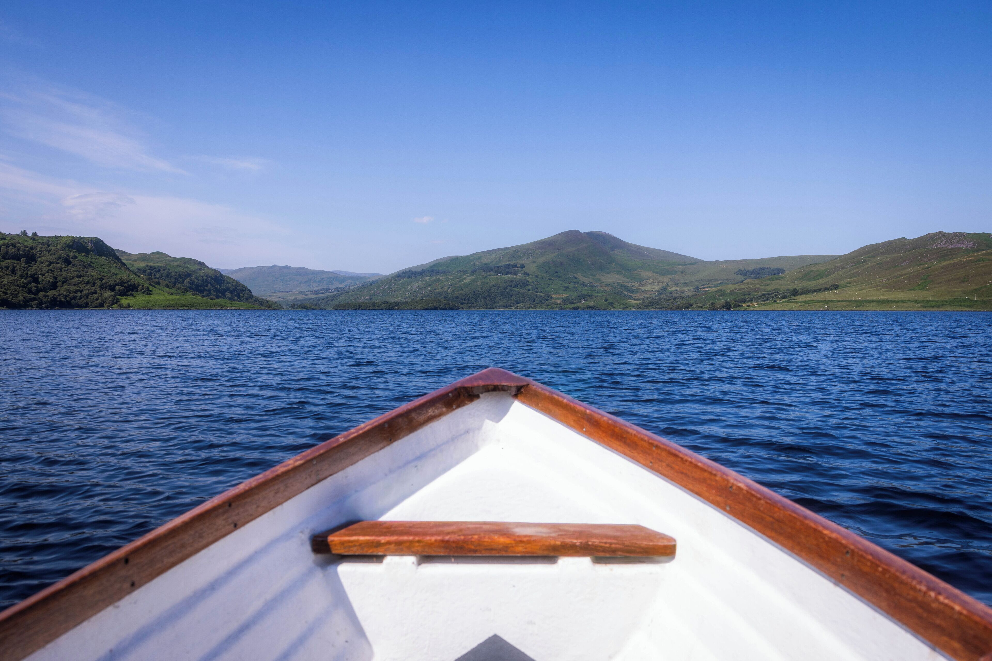 Interior de un barco con vista a un lago tranquilo y colinas distantes.
