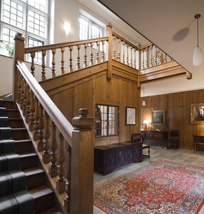Une pièce spacieuse avec un escalier en bois, une grande moquette et un bureau avec une lampe.