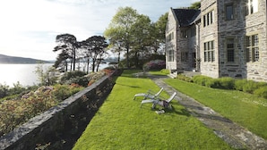 A stone building with a stone pathway leading to a grassy area with outdoor furniture.