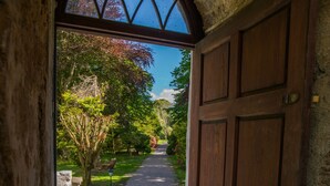 An arched doorway leading to a stone pathway surrounded by trees and a clear sky. - The Dunloe Hotel & Gardens (Dunloe Lower)