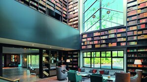 A spacious library with high ceilings, multiple bookshelves, comfortable seating areas, and large windows offering views of the outdoors. - The Dunloe Hotel & Gardens (Dunloe Lower)