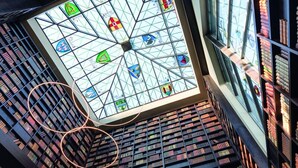 A library interior with a large skylight, bookshelves, and a circular light fixture. - The Dunloe Hotel & Gardens (Dunloe Lower)