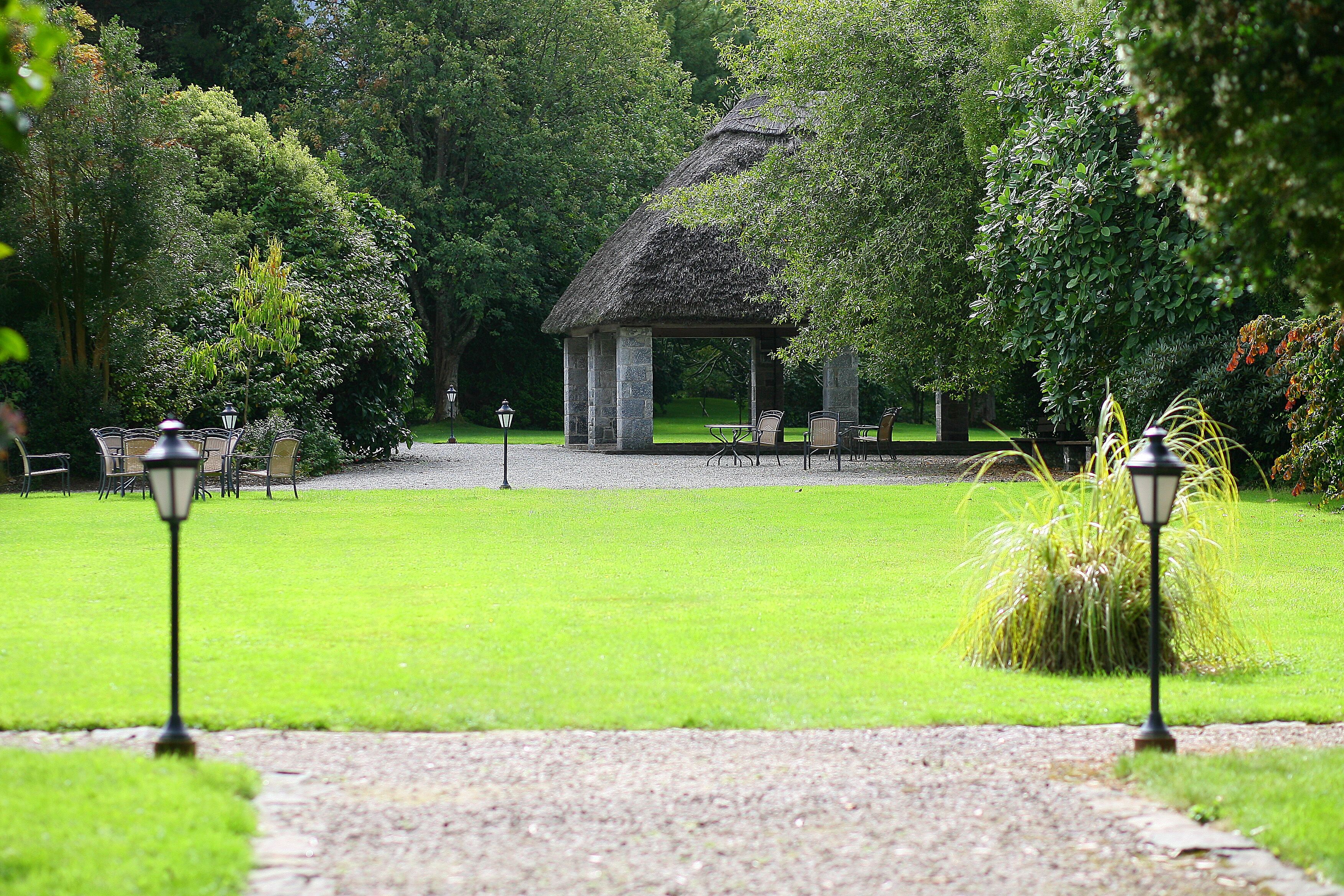 A garden with a gazebo, a gravel path, and outdoor seating.