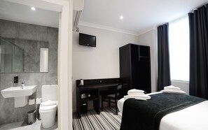 Ein Hotelzimmer mit Bad, Schreibtisch, Bett und Fernseher.