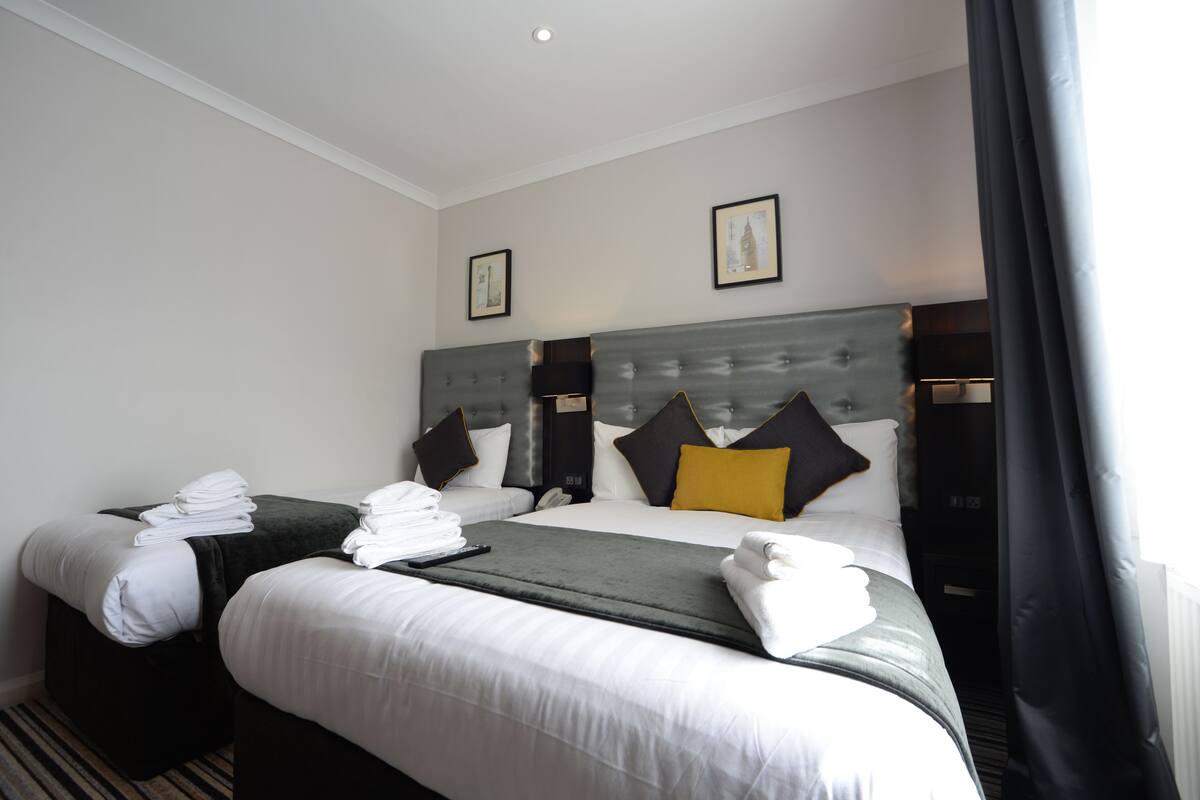 Ein Hotelzimmer mit zwei Betten, auf jedem Bett ordentlich gefaltete Handtücher und eine Fernbedienung.
