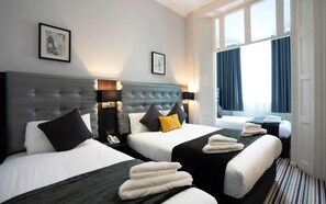 Een hotelkamer met twee bedden, een groot raam met gordijnen en uitzicht op de Eiffeltoren.
