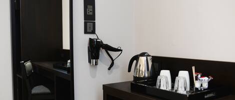 Quarto de hotel com escrivaninha, telefone e bandeja com xícaras e cafeteira.