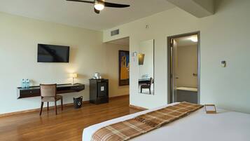 A hotel room with a bed, desk, chair, television, and a door leading to a bathroom.