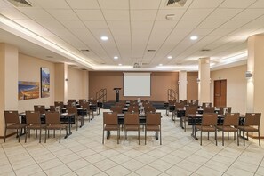 A conference room with multiple tables and chairs, a projector screen, and a large window. - Casa Andina Select Chiclayo (Chiclayo)
