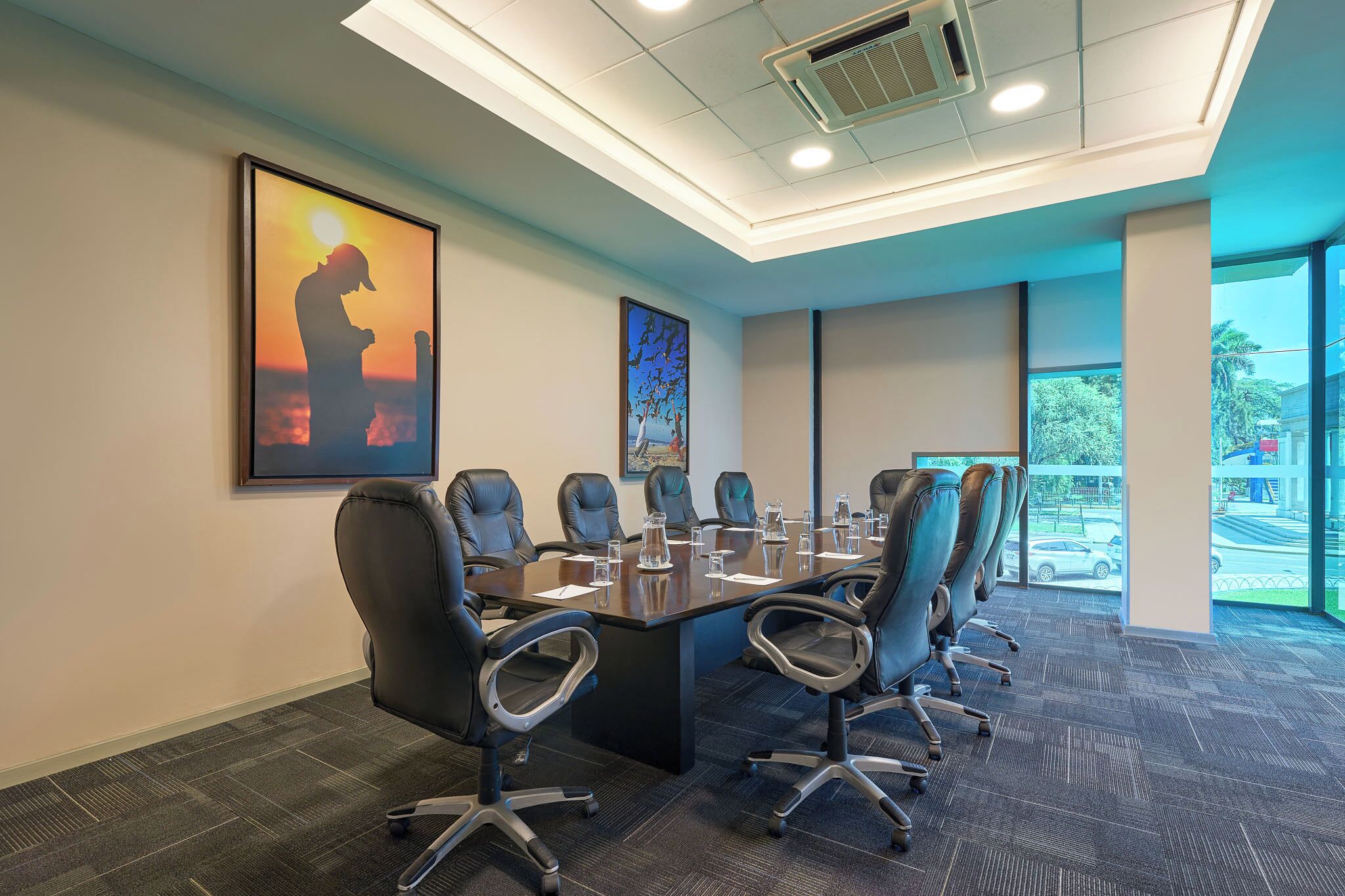 A conference room with a long table, multiple chairs, and artwork on the walls.