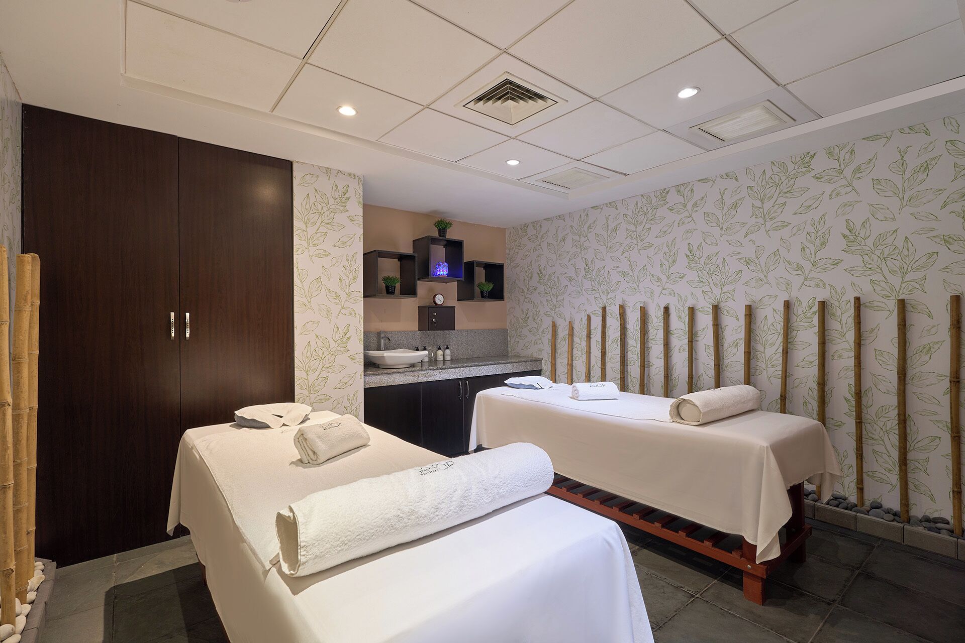 A hotel room with two beds, a bathroom, and a small kitchenette.