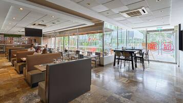 A restaurant interior with booths, tables, and a large window offering a view of the outside.