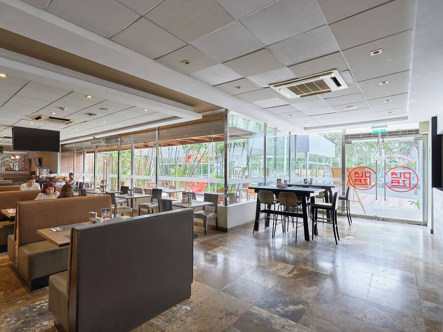 A restaurant interior with booths, tables, and a large window offering a view of the outside.