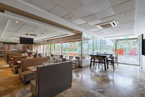 A restaurant interior with booths, tables, and a large window offering a view of the outside. - Casa Andina Select Chiclayo (Chiclayo)