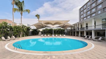 Una piscina al aire libre, sillones reclinables de piscina