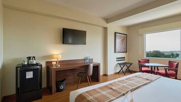 A hotel room with a bed, a desk, a chair, a TV, and a window with a view.