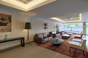 A modern living room with sofas, a coffee table, a floor lamp, and a bookshelf. - Casa Andina Select Chiclayo (Chiclayo)