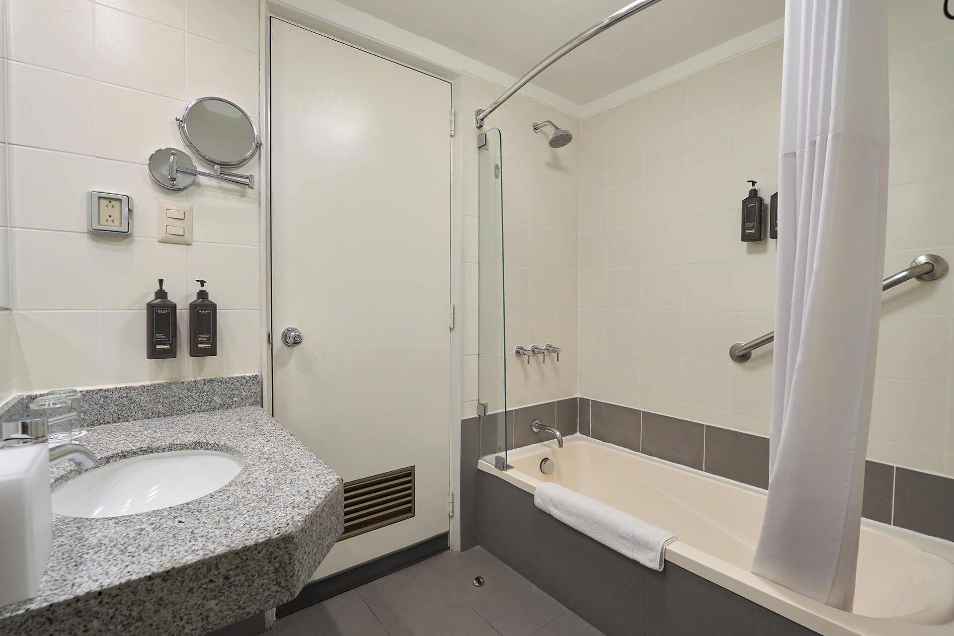 Ein Badezimmer mit Marmorplatte, Waschbecken, Duschkabine aus Glas und Badewanne.