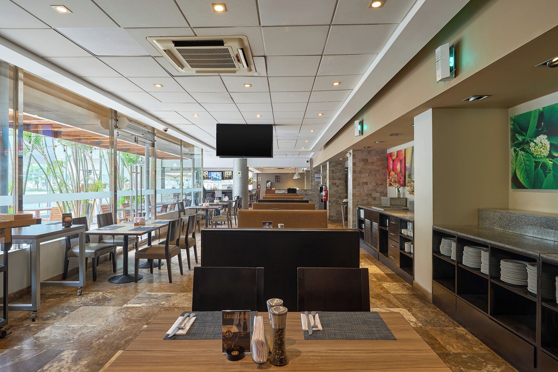 A restaurant with a long counter, multiple seating areas, and a large TV screen.
