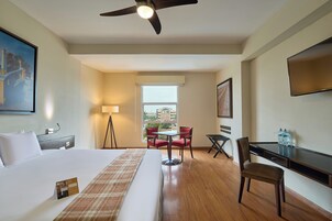 Una habitación de hotel con cama, escritorio, silla, mesa, lámpara y televisor.
