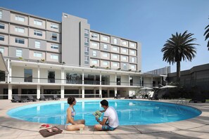 Una piscina al aire libre, sillones reclinables de piscina