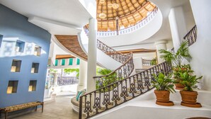 Un intérieur spacieux agrémenté d’un escalier en colimaçon, d’un banc et de plantes en pot.