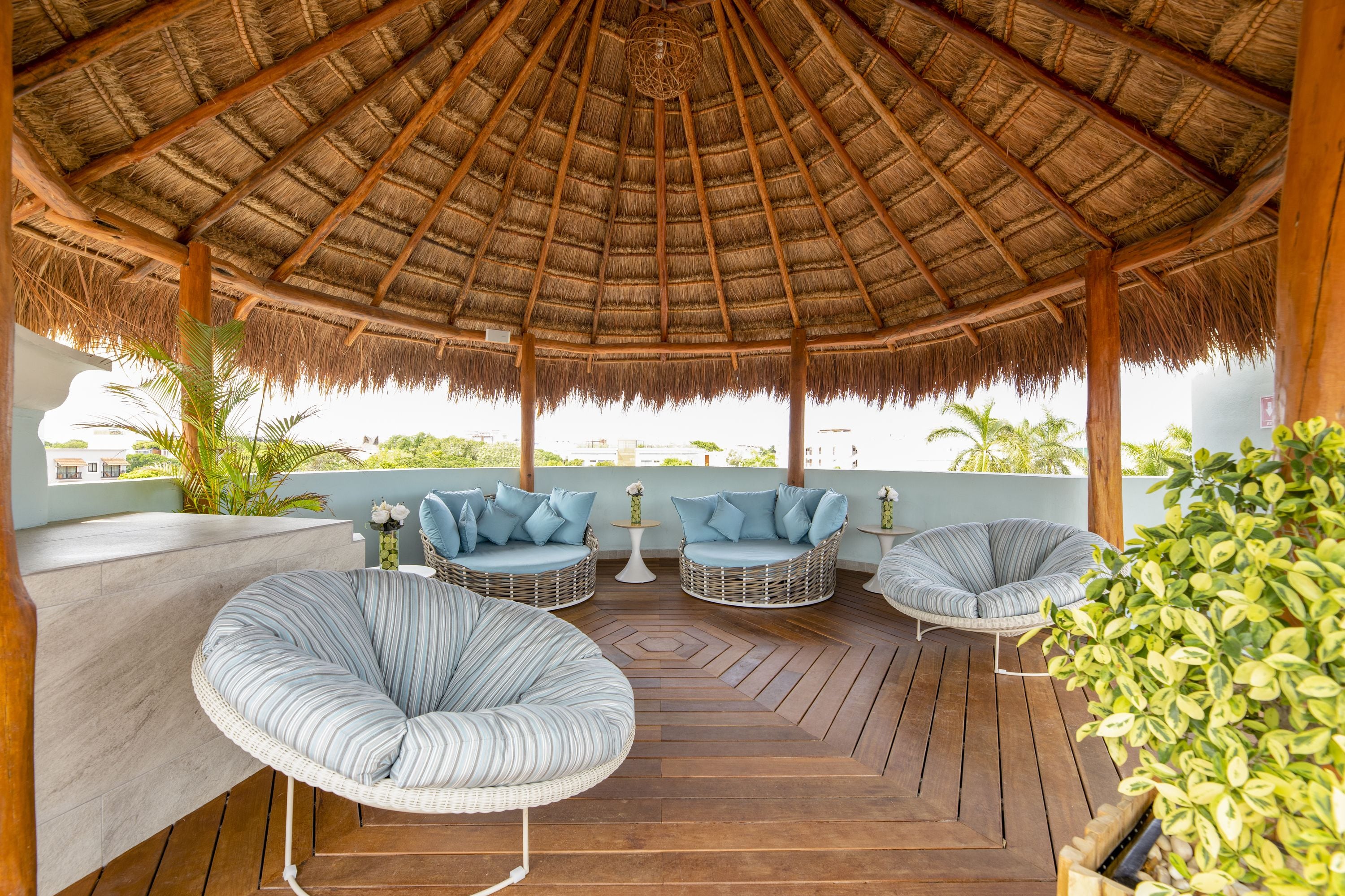 A covered outdoor seating area with wicker furniture and a thatched roof.