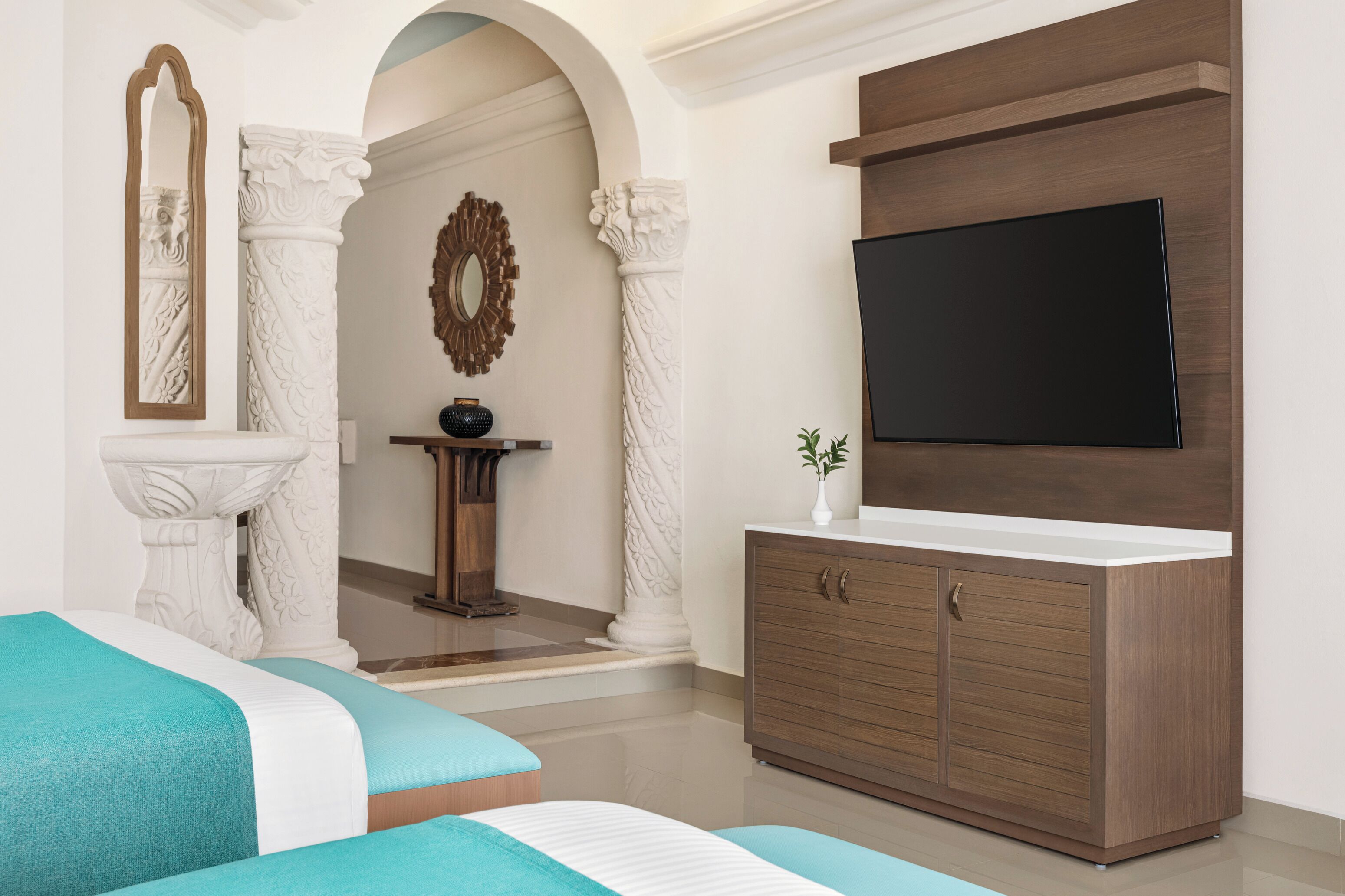 A modern bathroom with a large mirror, a sink, and a vanity with a flat-screen TV.