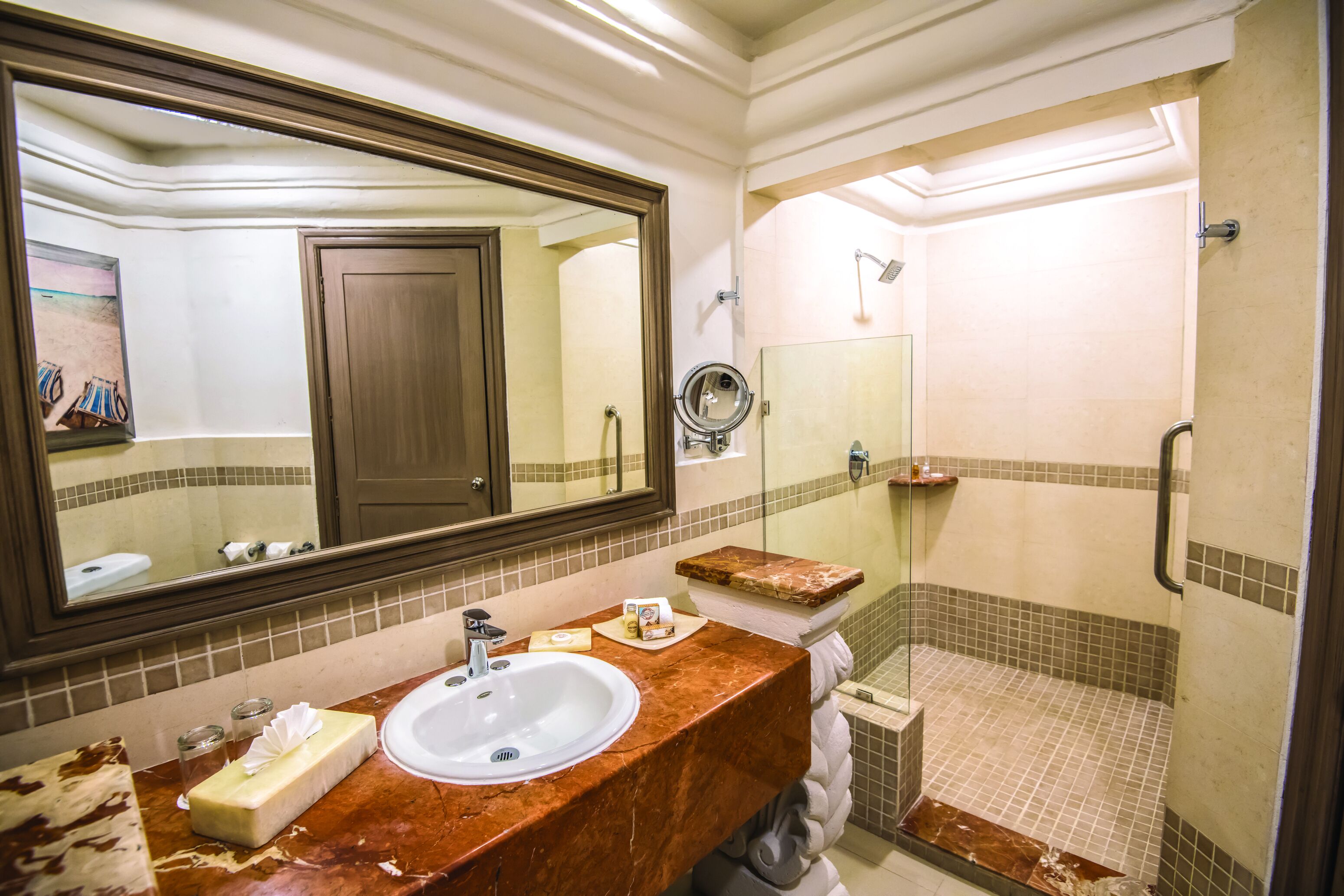 A bathroom with a marble sink, a large mirror, a shower, and a towel rack.