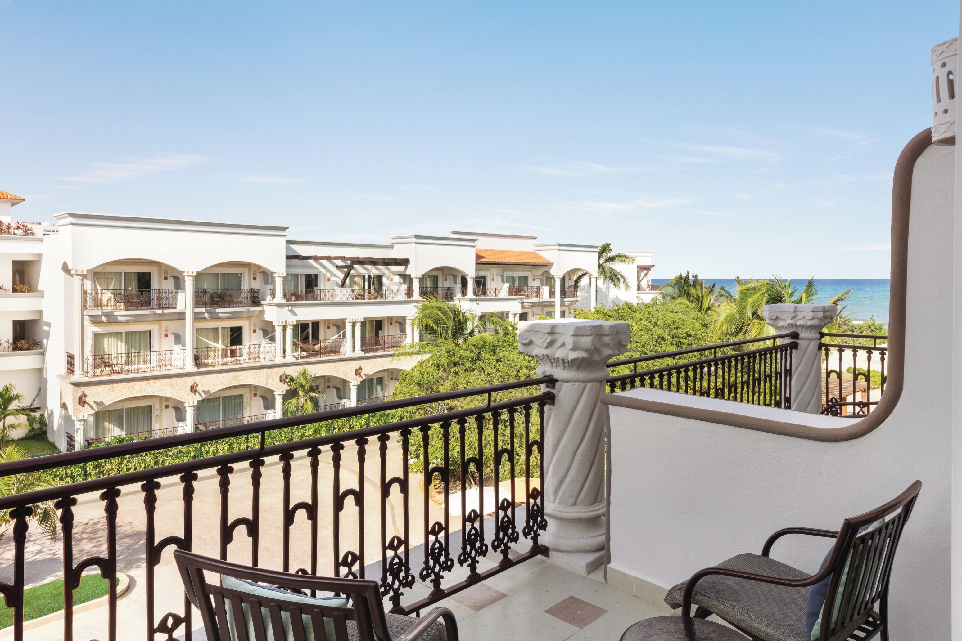 A balcony with a view of a hotel complex, featuring multiple balconies and a clear sky.
