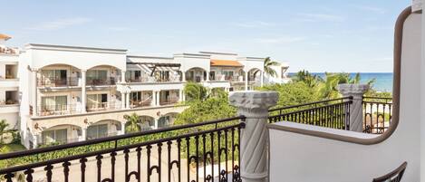 A balcony with a view of a hotel complex, featuring multiple balconies and a clear sky.