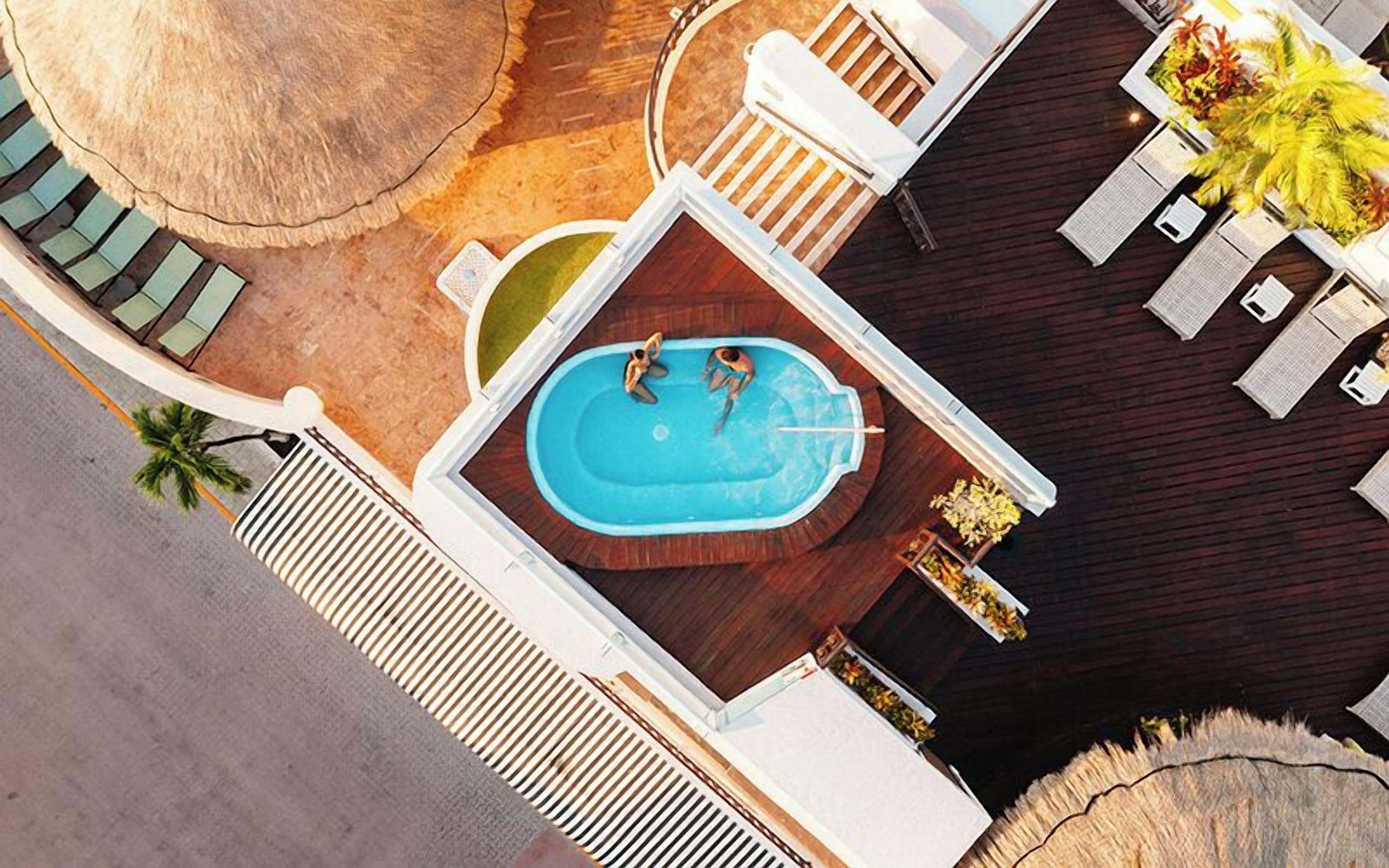 Vista aerea di una zona piscina sul tetto, con piscina, lettini e un’area bar.