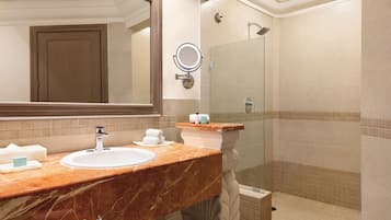 Une salle de bain avec un lavabo en marbre, un grand miroir, une douche et un porte-serviettes.