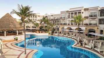 Een resort met een groot zwembad, loungegedeeltes en een bar.