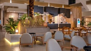 Un moderno vestíbulo de hotel con un mostrador de recepción, una zona de estar y una escalera.