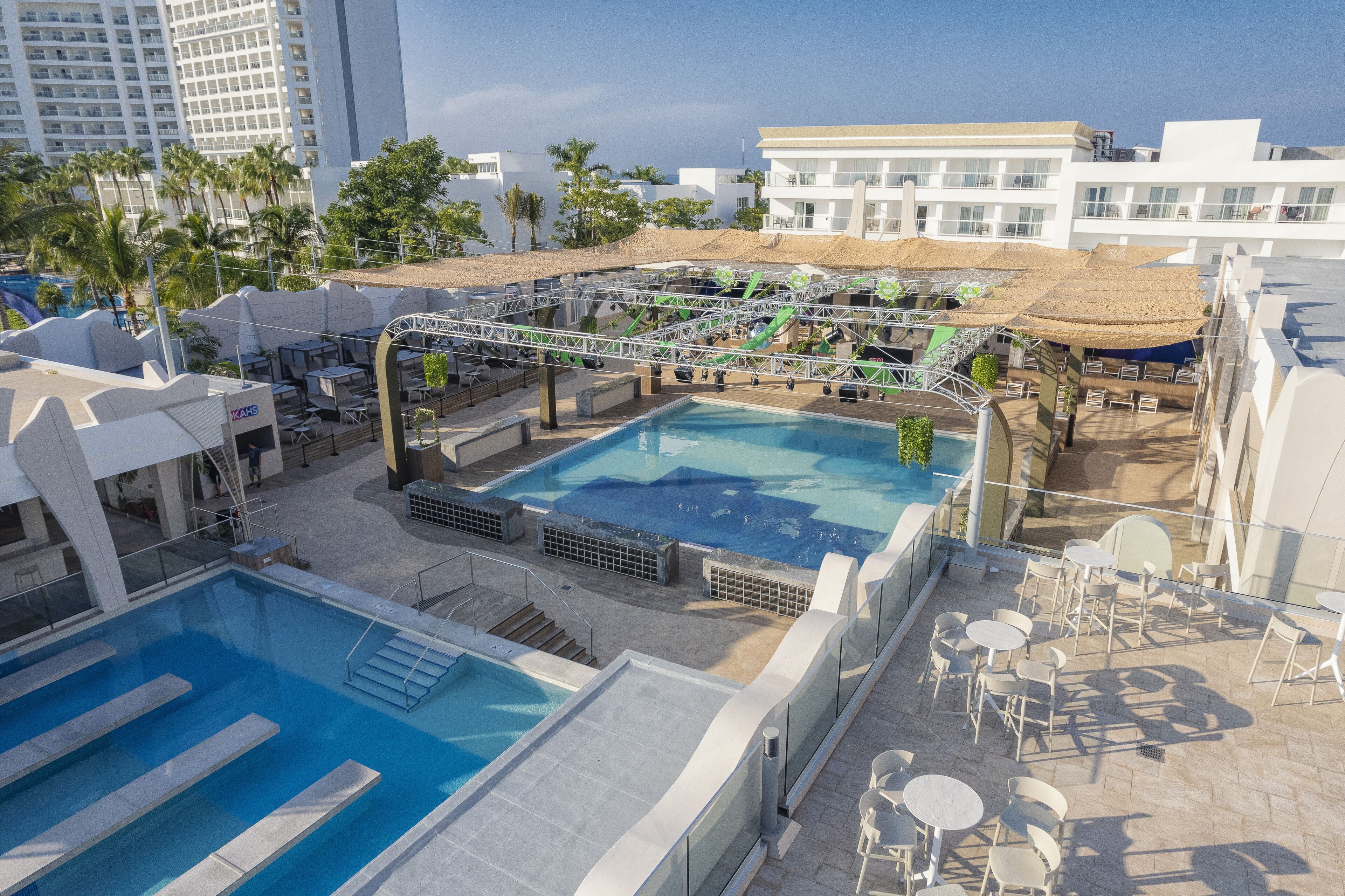 Zona de piscina en la azotea con plataforma de salto, sillas de descanso y vistas de los edificios circundantes.