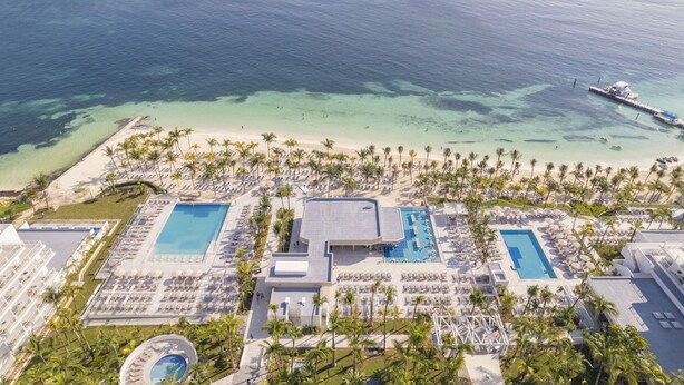 Vista aérea de un resort con varias piscinas, una playa y un muelle.