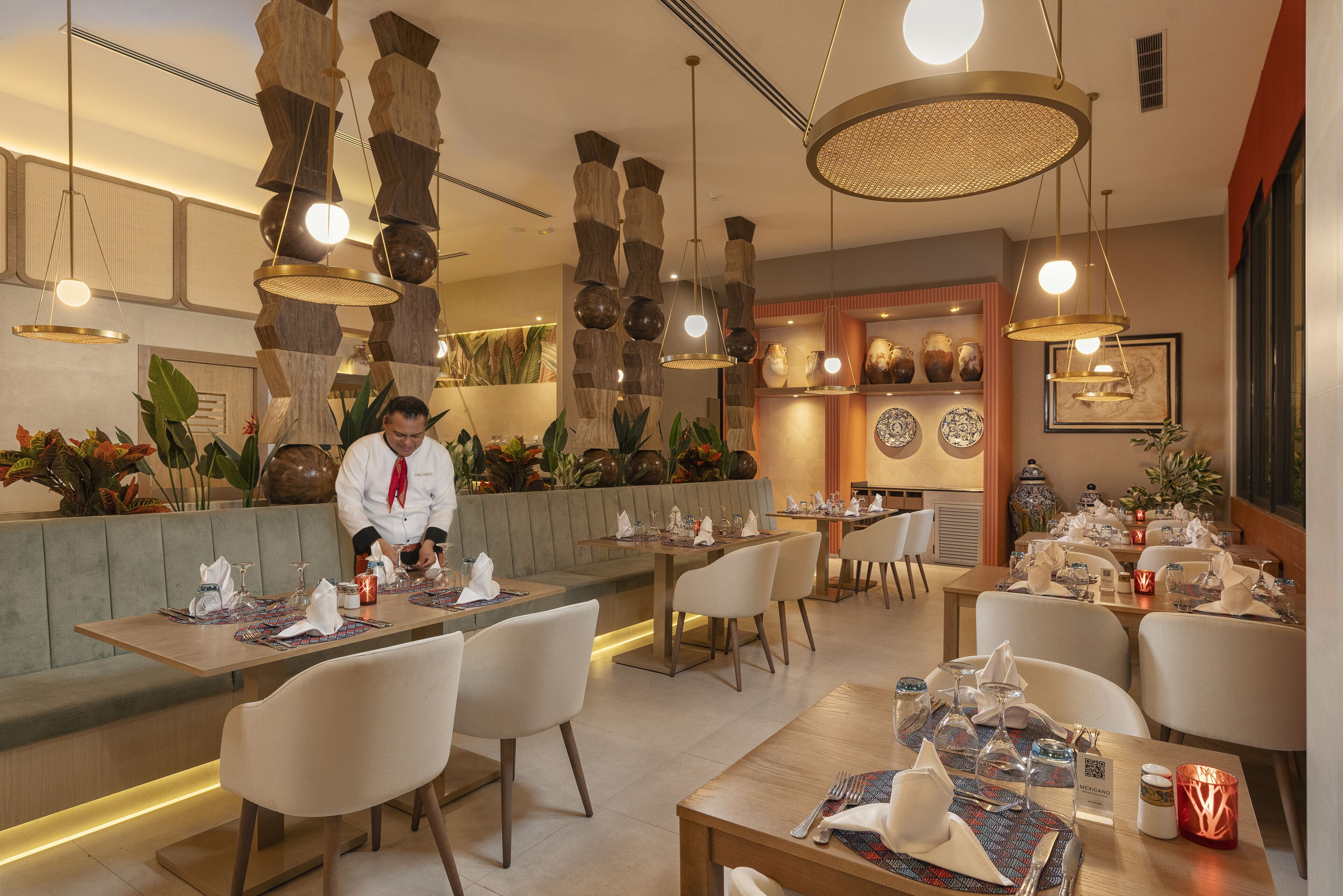 A restaurant with multiple dining tables, chairs, and a chef preparing food.