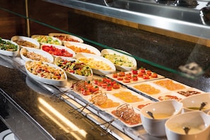 A buffet with various dishes including salads, pasta, and appetizers.