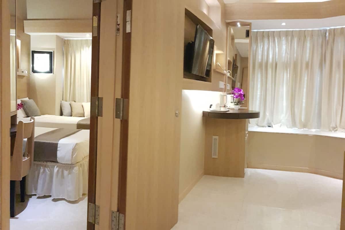 A hotel room with a bed, a desk, a mirror, and a window with curtains.